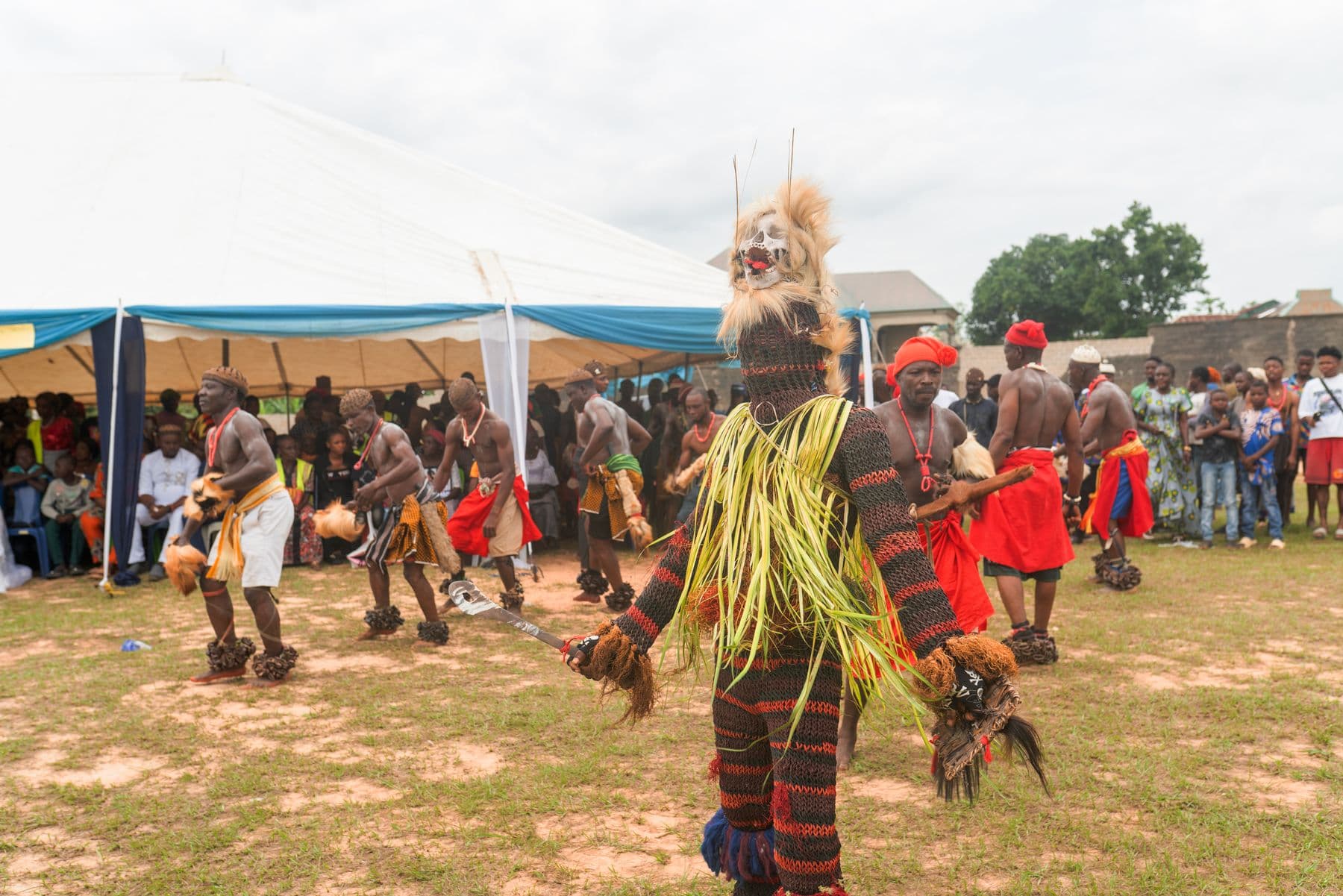A masquerade and dancers performing before a crowd at the Leboku festival