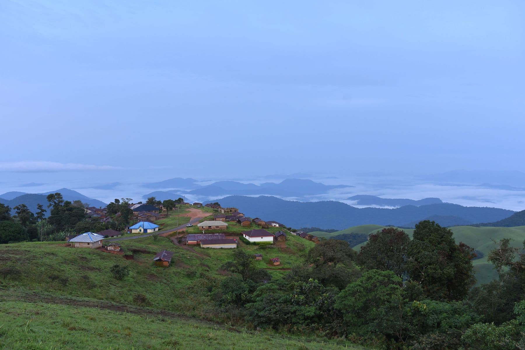 A hilltop settlement on the Obudu Plateau above a sea of morning cloud